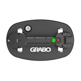 Top-down view of a black Grabo vacuum cleaner base on a solid white background, featuring a circular gauge, a green light, a red button, and the white Grabo logo.